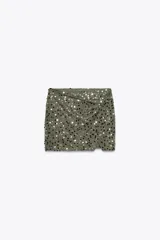 Falda pantalón verde militar con lentejuelas plateadas y negras, de tiro alto, con delantero cruzado y nudo.