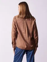 Camisa marrón de lyocell, marca Dash. Cuello con solapa y abertura central con botones. Largo de manga regulable con presilla y botón. Delantera con bolsillos aplicados.