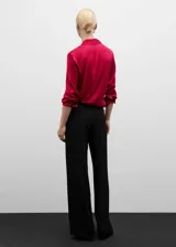 Camisa color crema de tejido fluido con textura y acabado satinado. Tiene cuello clásico, cierre de botones frontal y mangas largas con puños abotonados.