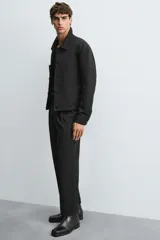 Pantalón negro relaxed fit confeccionado en tejido con algodón, lino y lyocell. Cintura con detalle de pliegues frontales dobles, bolsillos delanteros y traseros. Cierre frontal con cremallera y botón.
