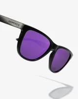 Lentes de sol Hawkers unisex, modelo One Raw, con montura cuadrada negra y lentes polarizadas color violeta.