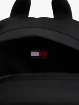 Mochila Tommy Jeans Essential negra con base color beige. Tiene un compartimento principal con bolsillo interior de malla, un bolsillo exterior con cremallera, asa superior y correas ajustables y acolchadas.