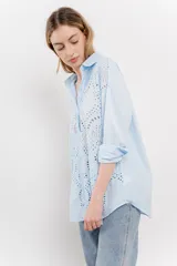 Camisa celeste de algodón con bordado calado tipo broderie, manga larga con puño angosto y botones al frente.