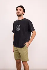 Remera negra con efecto gastado, corte amplio y estampado blanco en el pecho con motivos playeros.