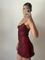 Vestido corto de fiesta color bordó, con lentejuelas, breteles finos y escote con encaje negro.