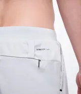 Bermuda deportiva gris con short de compresión negro incorporado, cintura elástica con cordón ajustable y bolsillos laterales con cremallera.