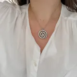 Collar plateado con dije en forma de espiral.