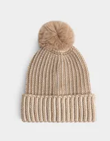 Gorro de lana tejido a crochet en color beige con detalles en blanco y pompón de piel sintética en la parte superior.