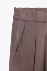 Pantalón palazzo color marrón topo, de tejido fluido, tiro medio, cintura elástica, bolsillos laterales y pinzas frontales.