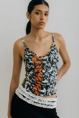Musculosa ajustada con tirantes finos y escote en V, con estampado abstracto en blanco y negro con franjas verticales naranjas y detalles dorados en los tirantes.