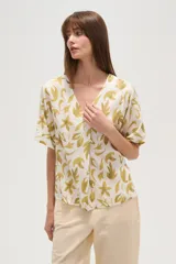 Blusa marrón con estampado de hojas color crema, cuello en V y mangas cortas. Corte holgado.