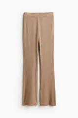 Pantalón largo color beige de punto acanalado con cintura elástica y corte ajustado hasta la rodilla, con terminación acampanada.