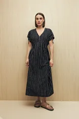 Vestido largo negro con estampado de líneas verticales blancas, escote en V, mangas cortas con lazo ajustable y corte fluido.