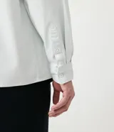 Camisa celeste de algodón, corte oversized, manga larga, cuello camisero, dos bolsillos frontales con solapa y cierre con botones.