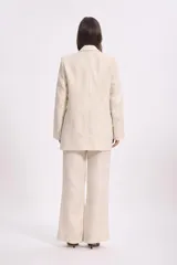 Blazer color crema con textura de lurex, solapas clásicas, corte recto y bolsillos delanteros.