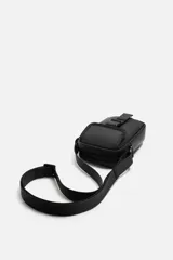 Bandolera vertical negra de acabado engomado con compartimento principal con cierre de cremallera y bolsillo interior plano. Bolsillo frontal con cierre de hebilla de liberación rápida. Asa de hombro ajustable y extraíble.