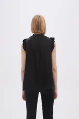 Blusa sin mangas color crudo con cuello con lazo y volados en los hombros.