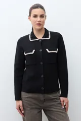 Chaqueta de tejido color terracota/lacre, con cuello y bordes de bolsillo en blanco con textura de punto. Posee cierre frontal de botones y manga larga.