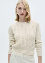 Sweater color crema de tejido de punto grueso con diseño trenzado y calado. Tiene cuello redondo y terminaciones acanaladas.