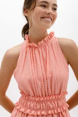 Vestido corto color salmón, con escote halter con volados y falda escalonada con volados.