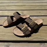 Sandalias de cuero sintético color verde militar, con plantilla marrón y hebillas metálicas doradas.