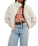 Campera cropped de faux-sherpa color blanco, con cierre frontal de cremallera, cordones trenzados con pompones, cuello alto y bolsillos laterales.