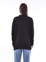 Saco color beige de tejido de punto, con cuello abierto, bolsillos frontales y mangas largas con detalle de botones en los puños.
