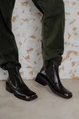 Botas Chelsea de cuero color marrón con elástico lateral negro, puntera metálica cuadrada y suela track.