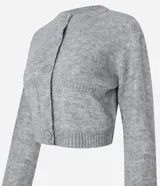 Cardigan cropped de punto color gris con cuello redondo, manga larga, cierre frontal con botones y bolsillos delanteros.