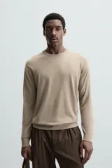 Jersey de hombre color beige claro, tejido en lana, de corte recto, cuello redondo y mangas largas con terminaciones en rib.