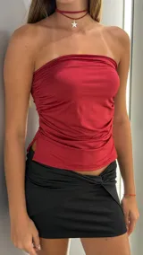 Top strapless color bordó, ajustado al cuerpo, con frunces laterales y aberturas en el ruedo inferior.