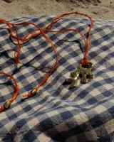 Collar con dije de bronce macizo con forma orgánica o de coral, suspendido de un hilo de seda natural color naranja.