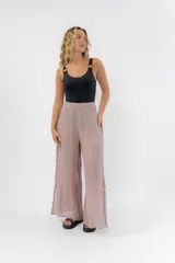 Pantalón de gasa color rosa con cintura elástica y aberturas laterales con detalle de pompones.