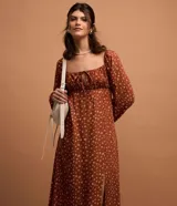 Vestido midi color ladrillo con estampado floral blanco, escote cuadrado con lazo ajustable, mangas largas abullonadas y abertura lateral en la falda.