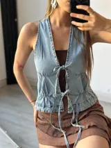 Chaleco de jean celeste con escote en V y lazos frontales.