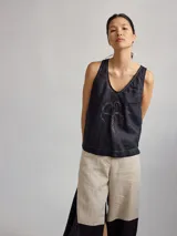 Top color rosa pálido de lino con cuello en V y bordado de un trébol de cuatro hojas en el centro.