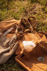 Cartera tote de gamuza color camel, con doble asa de hombro, bolsillo externo y detalle de borla colgante.