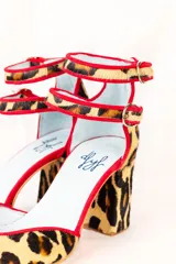 Zapato de tacón con estampado animal print, con doble tira en el tobillo y ribete rojo.