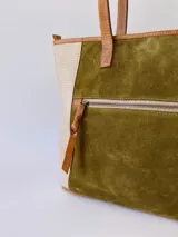 Bolso tipo tote de cuero color verde oliva con laterales de cuero texturizado color beige y manijas de cuero color marrón.