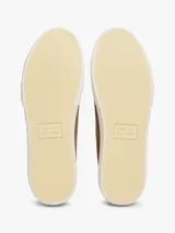 Zapatillas bajas de lona color marrón, con cordones y suela de goma vulcanizada color blanco. Presentan costuras contrastantes en blanco y detalles distintivos de la marca en la entresuela.