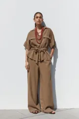 Pantalón marrón de tiro alto con cintura elástica, bolsillos delanteros y pernera ancha.