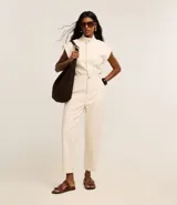 Mono largo color crema de sarga de algodón con elastano, cuello alto con botón, sin mangas, bolsillos laterales y trabillas en la cintura.