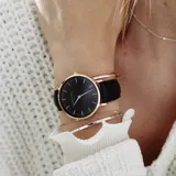 Reloj Rosefield modelo The Bowery con caja redonda de acero color oro rosa de 38mm, esfera negra minimalista, agujas doradas y correa de cuero negro. Resistencia al agua 3 ATM.