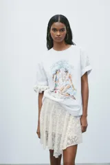 Camiseta blanca de corte recto y manga corta, con cuello redondo. Estampado frontal con dos mujeres en la playa y texto "Beach Days Best Days".