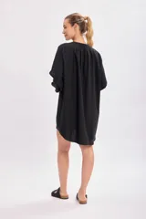 Vestido negro con mangas de volumen, cuello redondo y botones en la parte frontal.