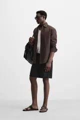 Bermuda regular fit negra confeccionada en tejido de lino. Cintura elástica ajustable con cordón y pliegues frontales. Bolsillos frontales y detalle de bolsillos traseros de plastrón.