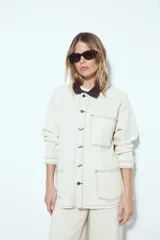 Sobrecamisa tipo barn jacket color negro, de algodón con elastano, con silueta relajada y estructura firme. Presenta cierre frontal con botones metálicos, cuello marrón, bolsillos aplicados y pespuntes visibles en color marrón.