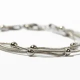 Pulsera plateada de acero con tres hilos y bolitas.