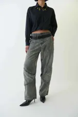 Pantalón jean gris de tiro medio con calce amplio, bolsillos delanteros y traseros, recortes en las piernas, trabillas para cinturón y cierre con botón y cremallera.