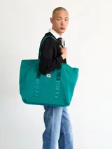 Bolso tote negro de Carhartt WIP, modelo Canby. Confeccionado en tafetán de nailon ligero, con compartimento principal con cierre de botón a presión, bolsillo interior con cremallera y bolsillo exterior. Asas de cincha resistentes y etiqueta cuadrada de Carhartt.